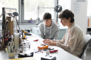 two students sitting at a computer desk 